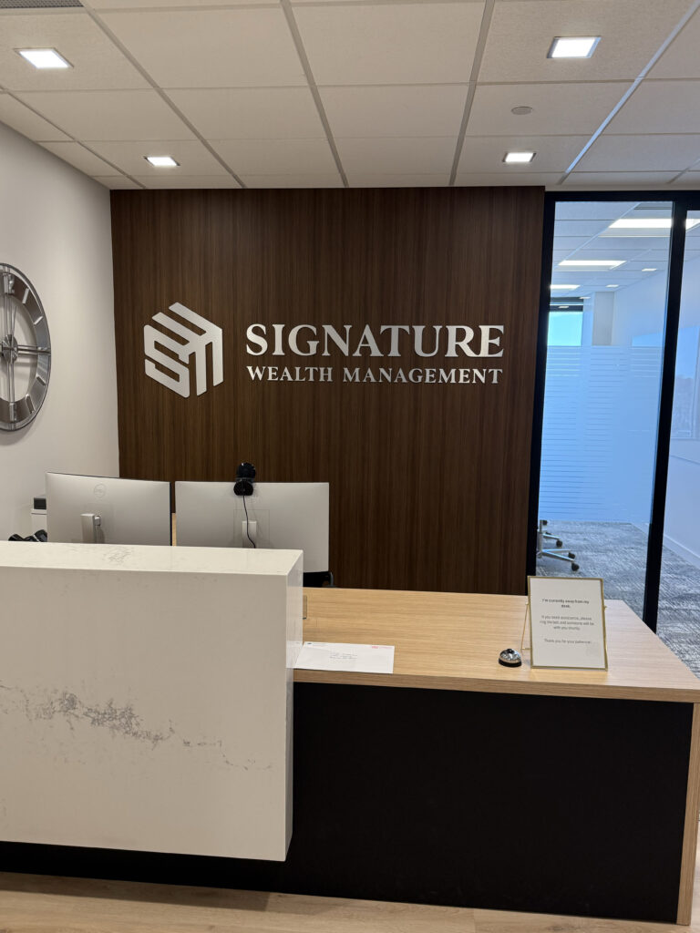 Signature Wealth Management A picture of the front desk with Signature Wealth Management behind the desk on a wall.