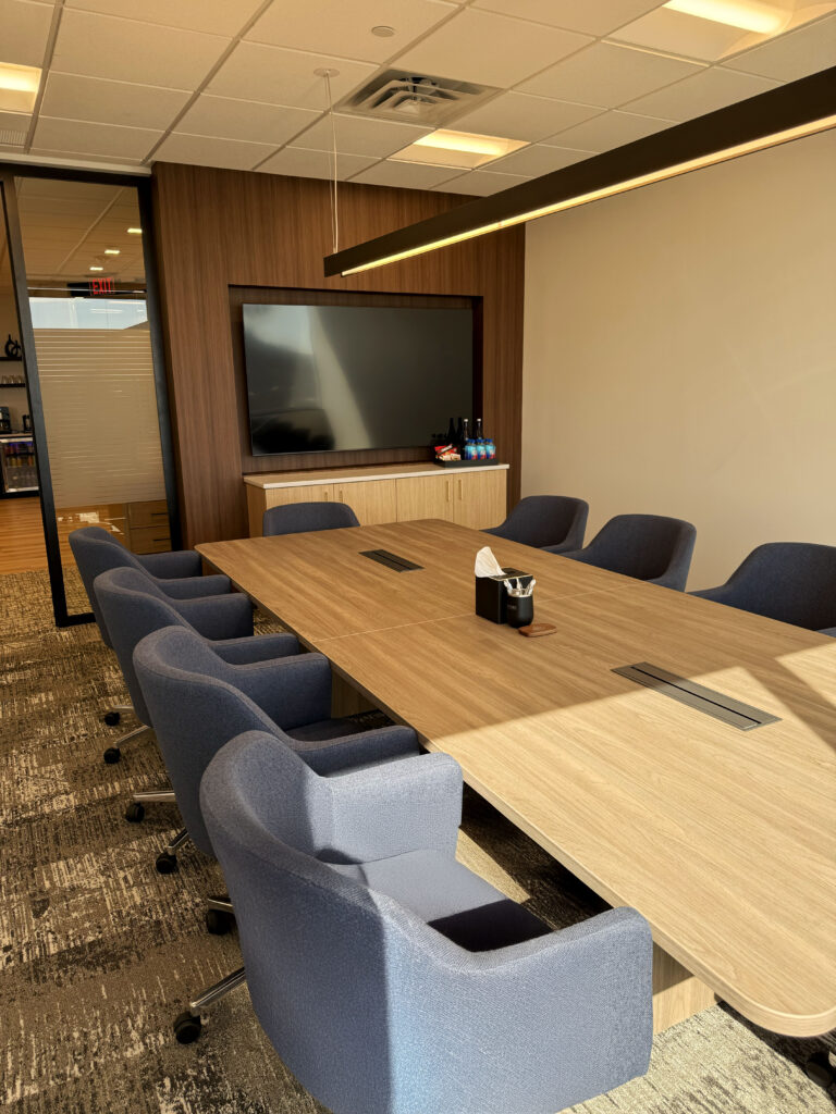 Signature Wealth Management Signature Wealth Management board room with a TV on the wall and sun coming in through the window and onto the table.