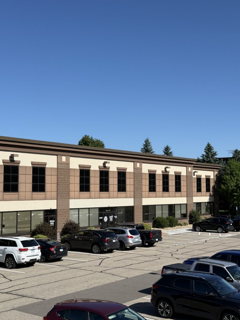 Modern two-story commercial office building with professional office suites, large parking lot, and landscaped grounds.